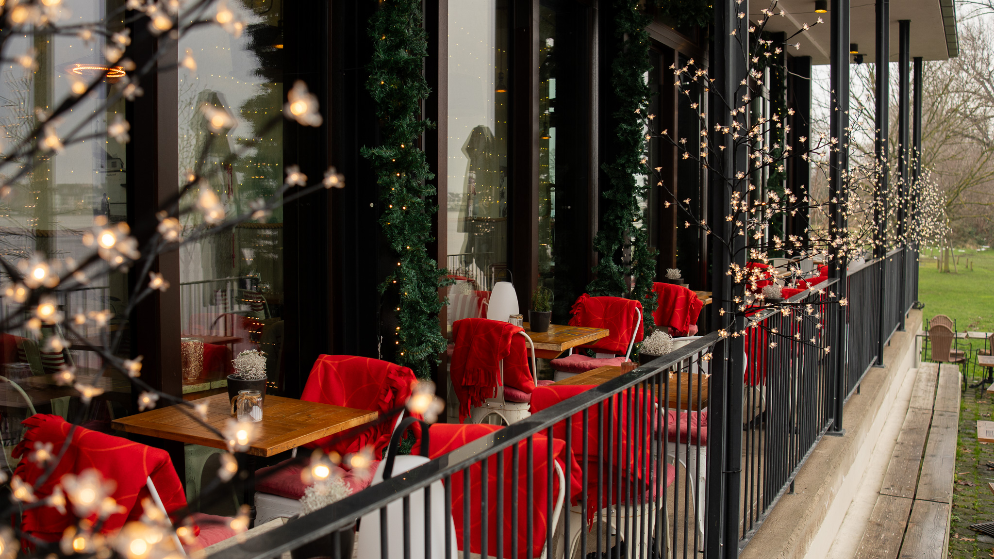 Festlich dekorierte Restaurant-Terrasse mit Lichterketten und roten Stühlen