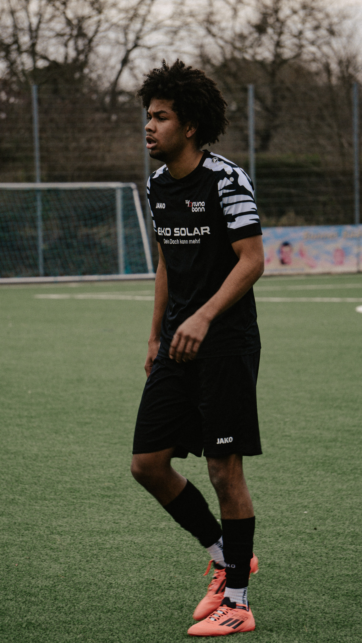 Fußballspieler auf dem Rasen in schwarzem Trikot