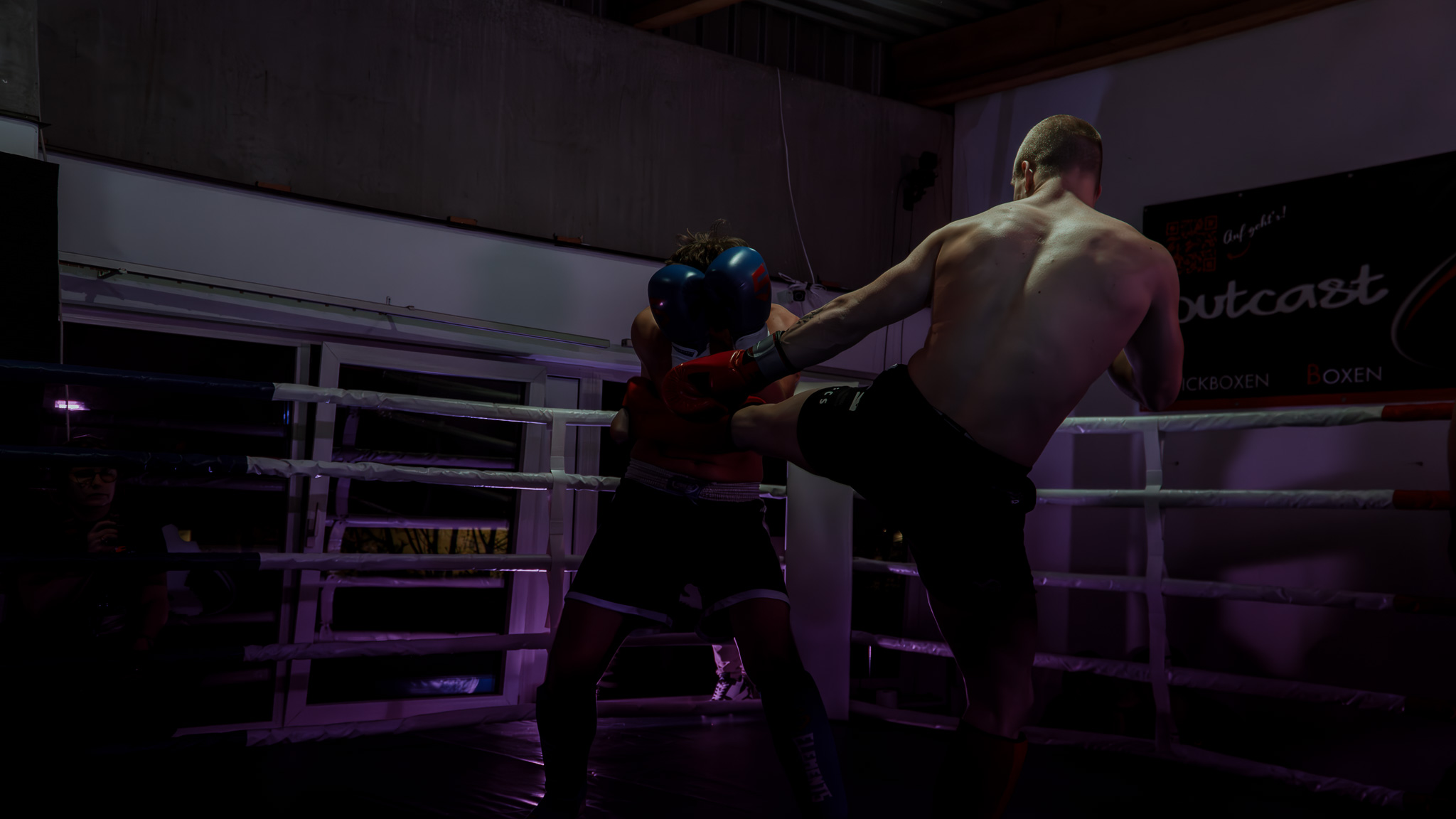 Boxkampf im Ring unter violettem Licht