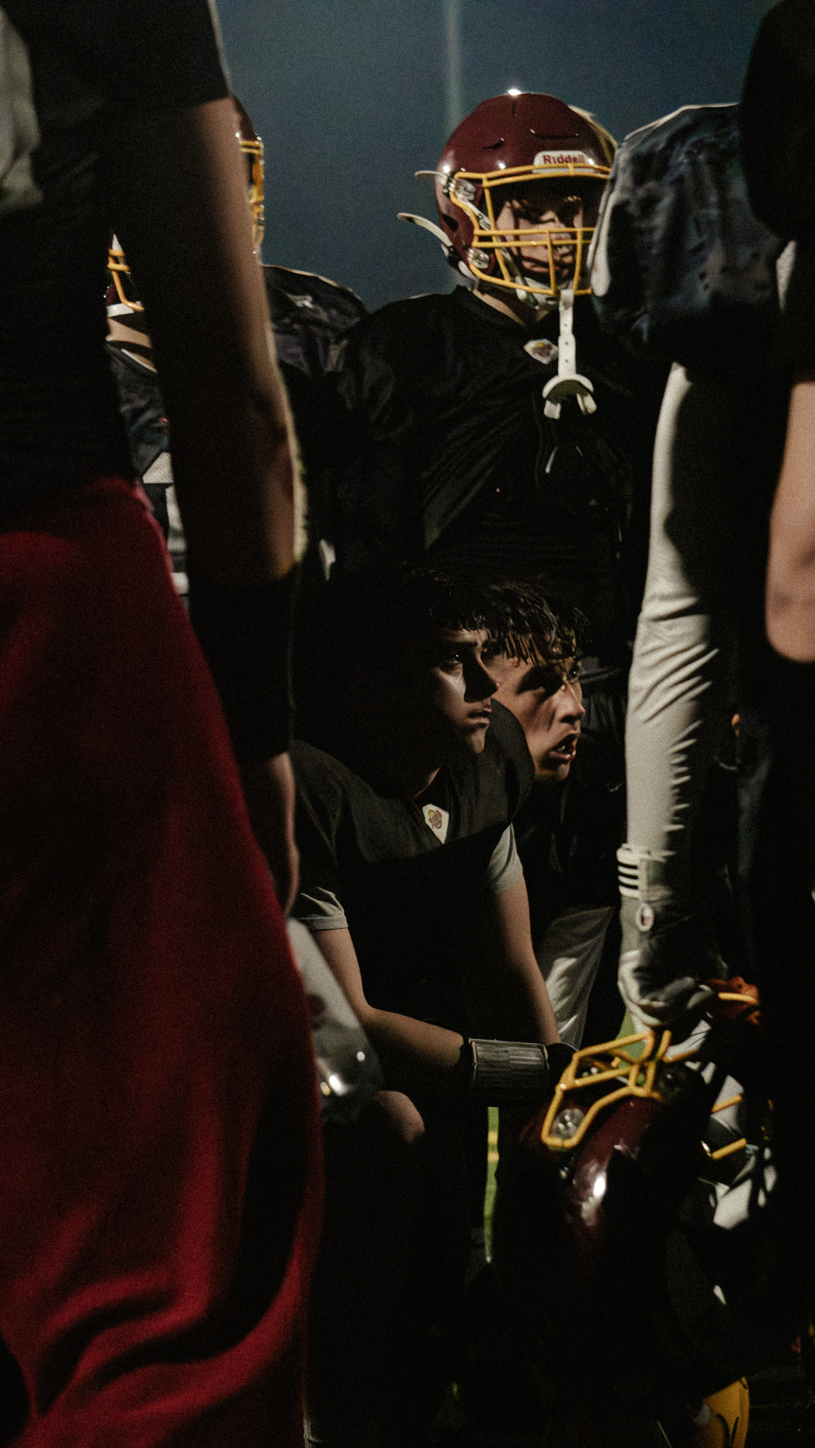 American-Football-Team im Huddle unter dramatischem Licht