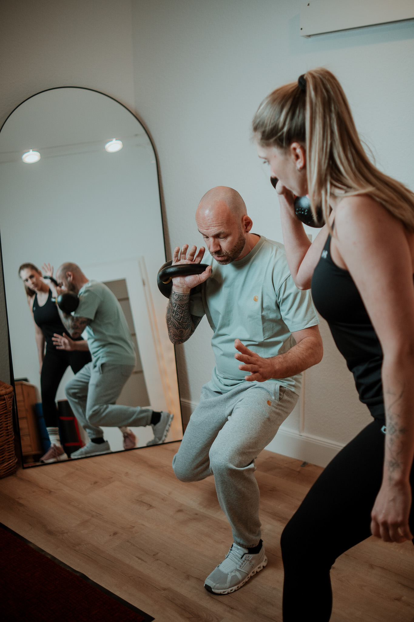 Personal Trainer und Klientin beim Kettlebell-Training vor dem Spiegel