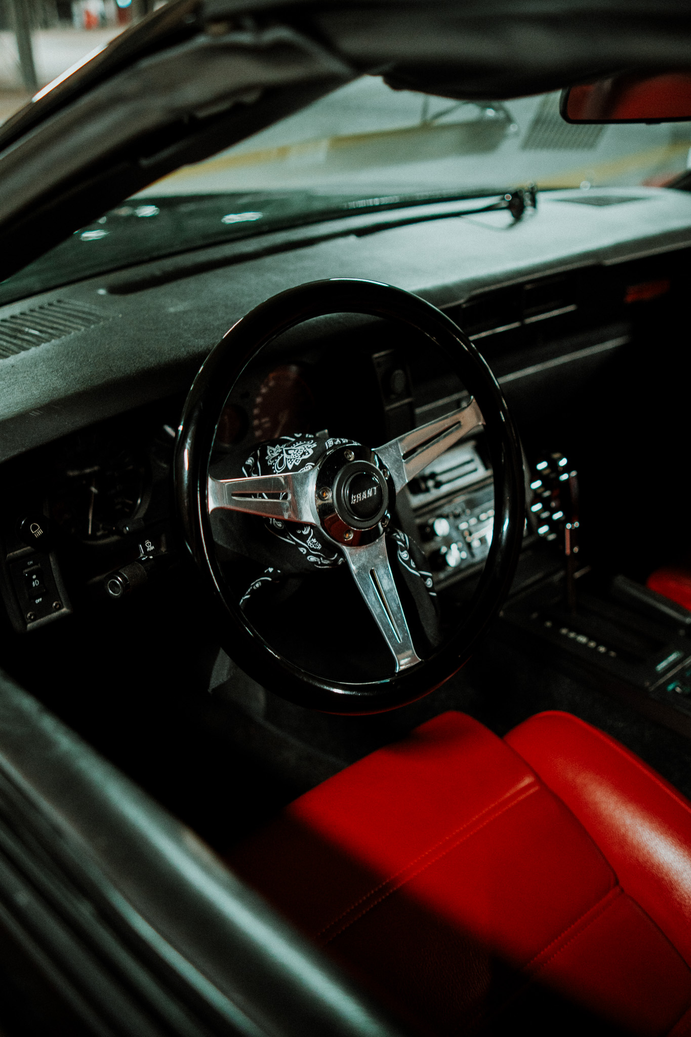Cockpit eines klassischen Autos mit Sportlenkrad und rotem Lederinterieur